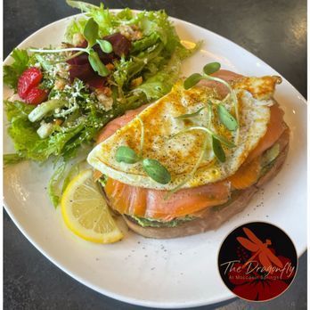 A white plate topped with a sandwich and a salad.