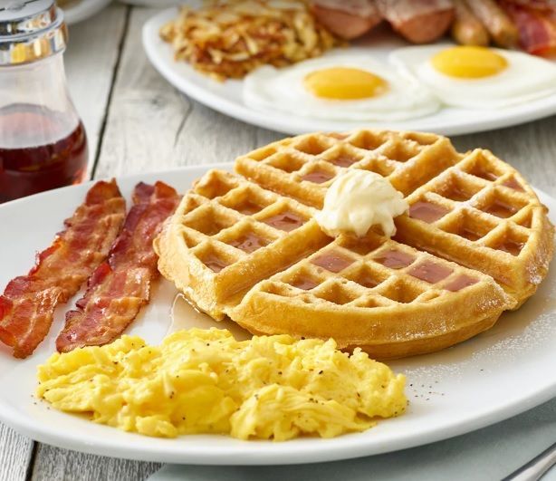 A waffle with bacon and scrambled eggs on a plate