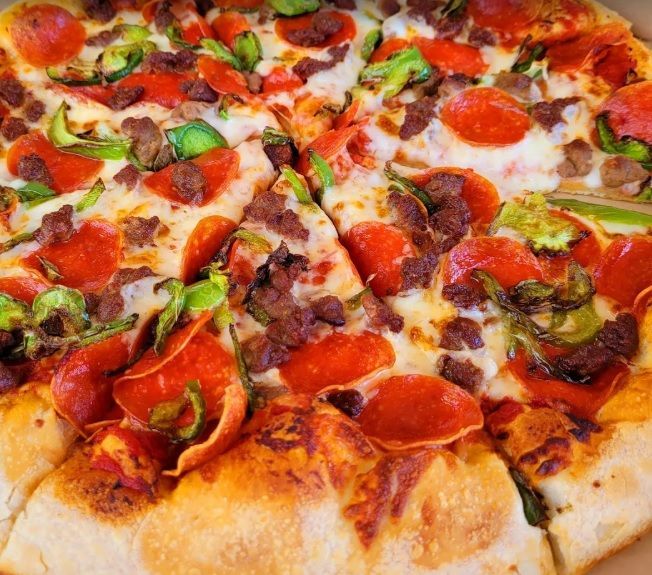 A person is holding a piece of pizza in their hand.