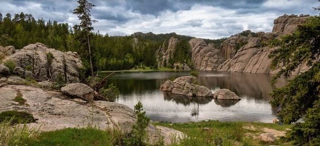 A lake surrounded by rocks and trees in the middle of a forest.
