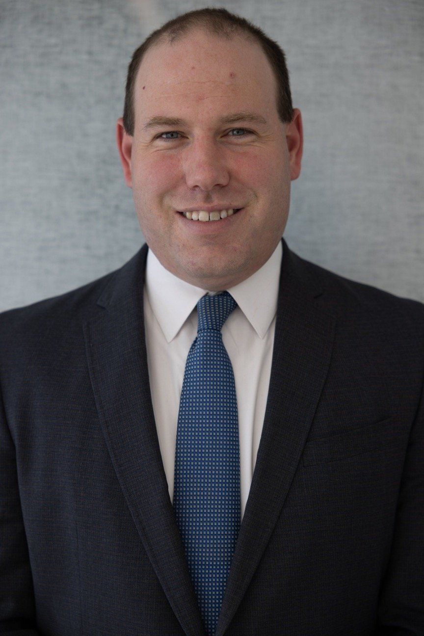 A man in a suit and tie is smiling for the camera