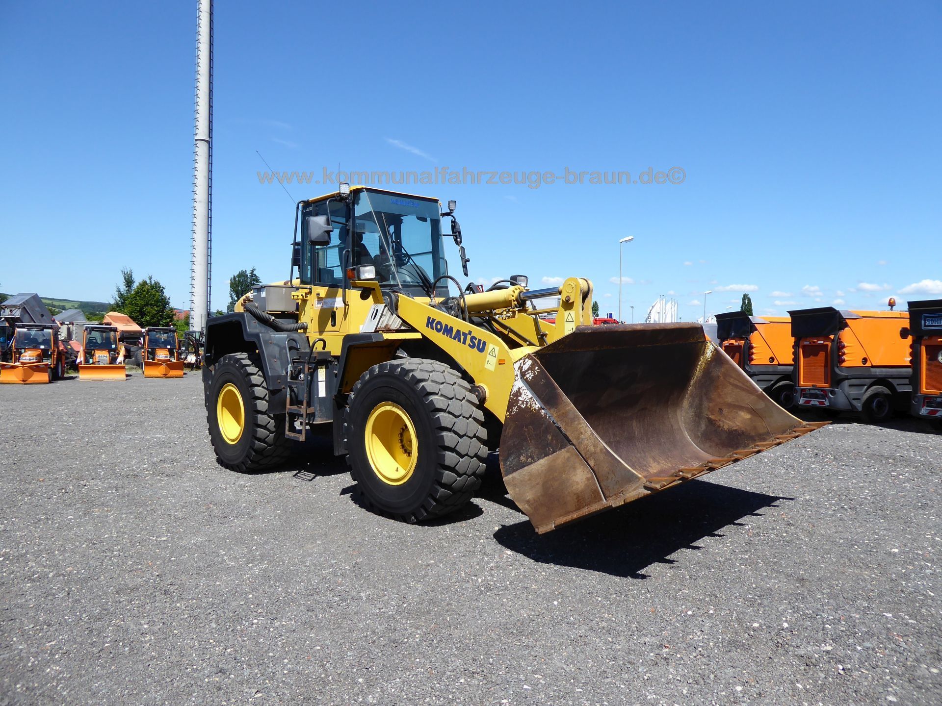 A yellow and black komatsu wheel loader is parked in a gravel lot.