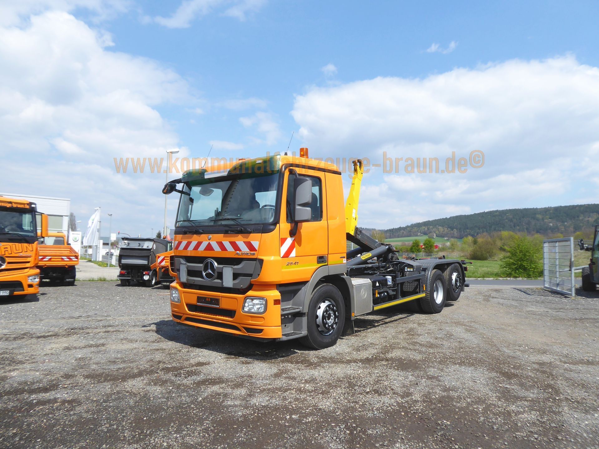 An orange dump truck is parked in a gravel lot.
