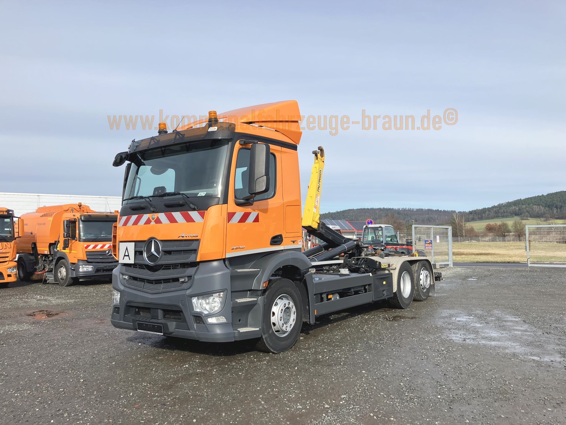 A large orange dump truck is parked in a parking lot.