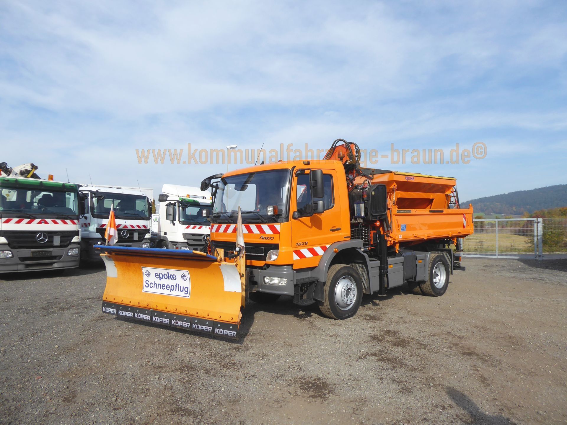 An orange truck with a snow plow attached to it