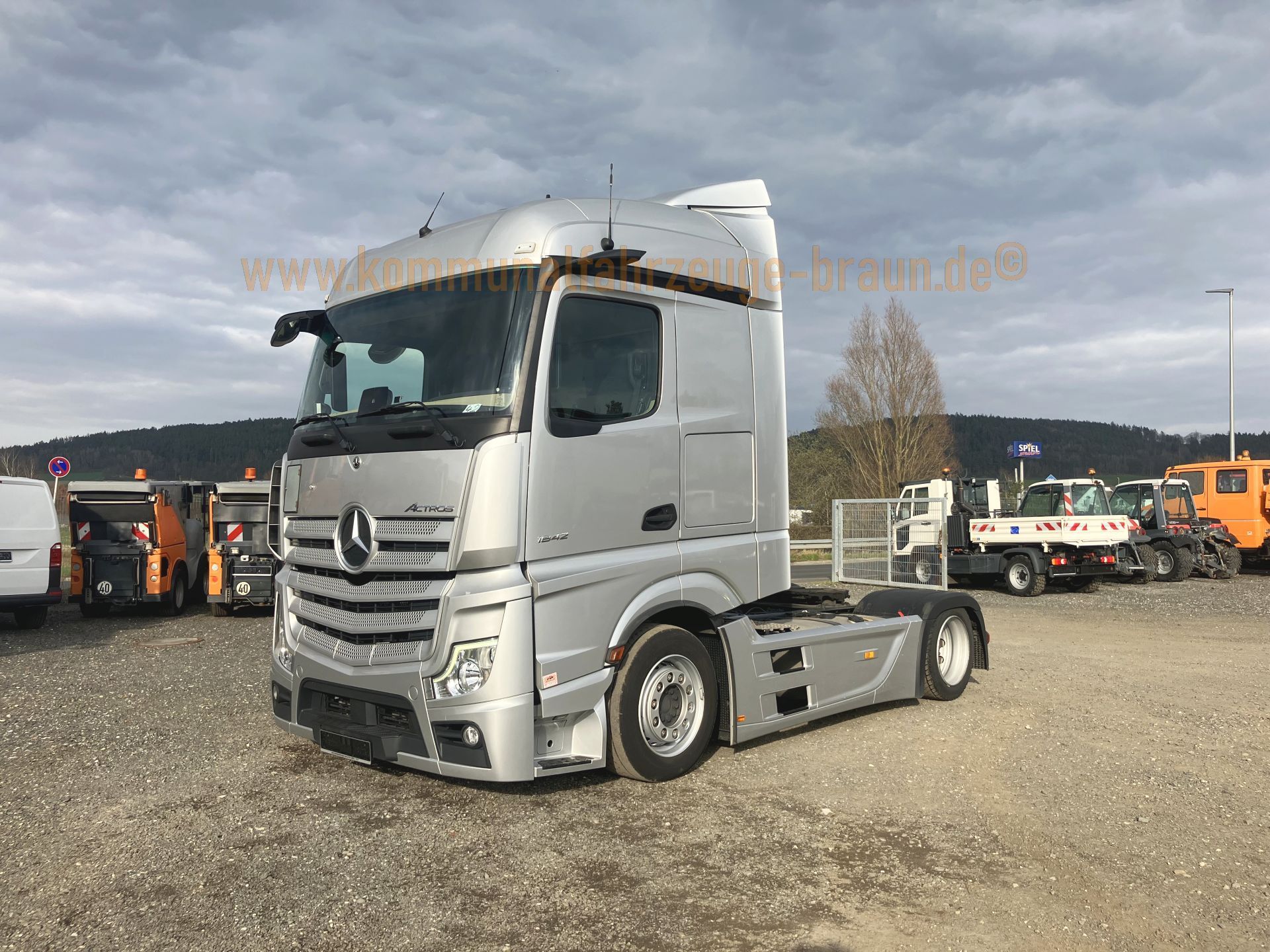 A silver semi truck is parked in a parking lot.