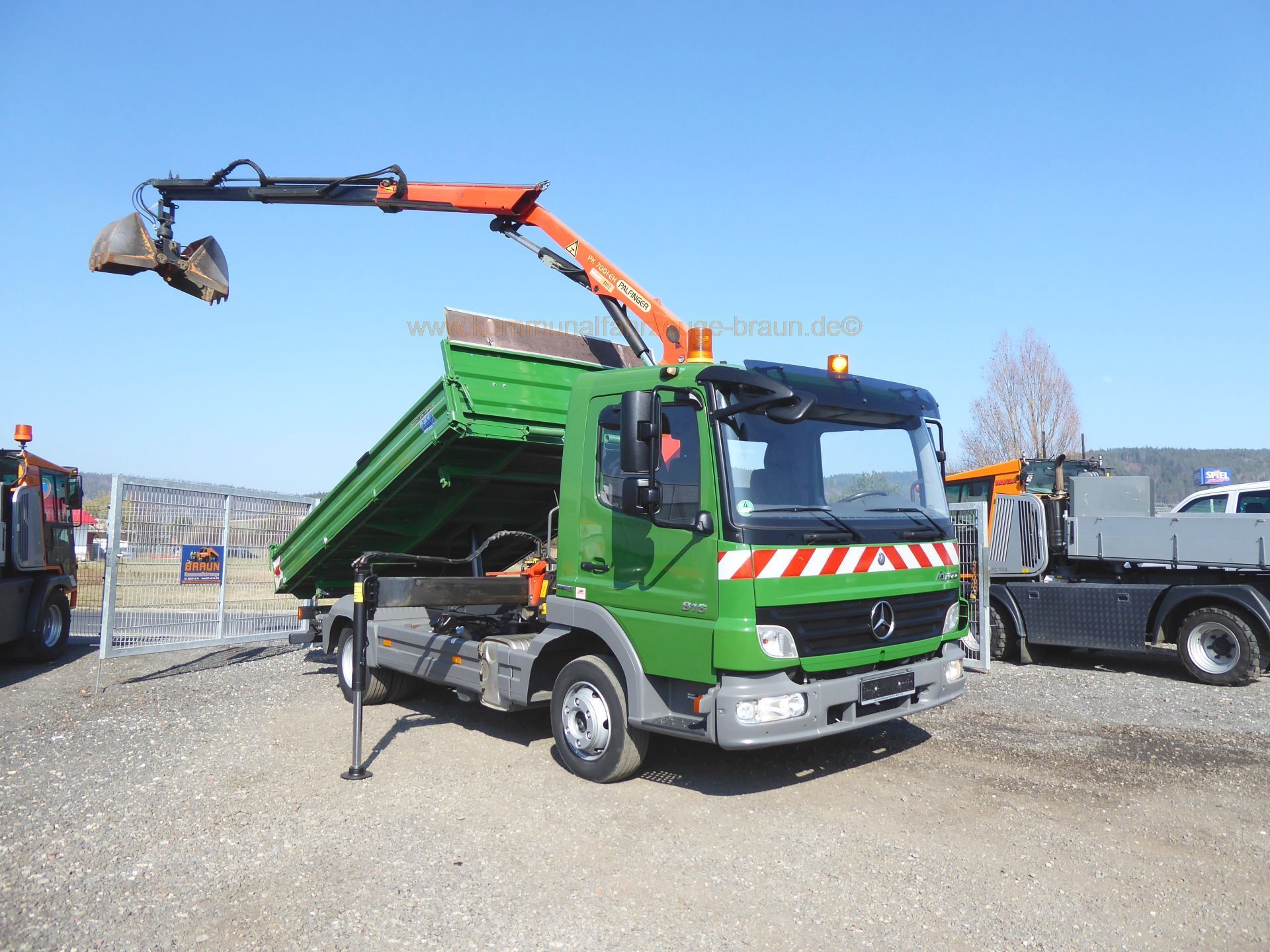A green dump truck with a crane attached to it