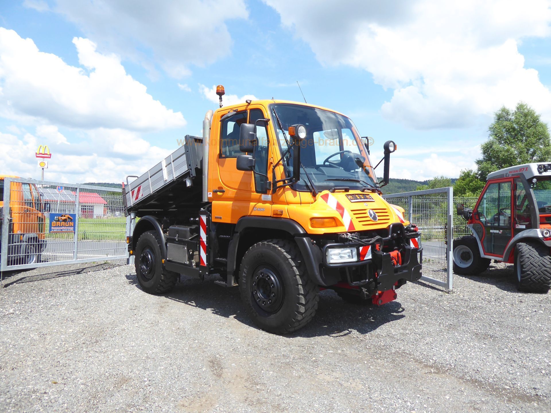 A yellow dump truck is parked in a gravel lot.