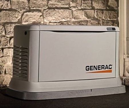 A generac generator is sitting in front of a stone wall.