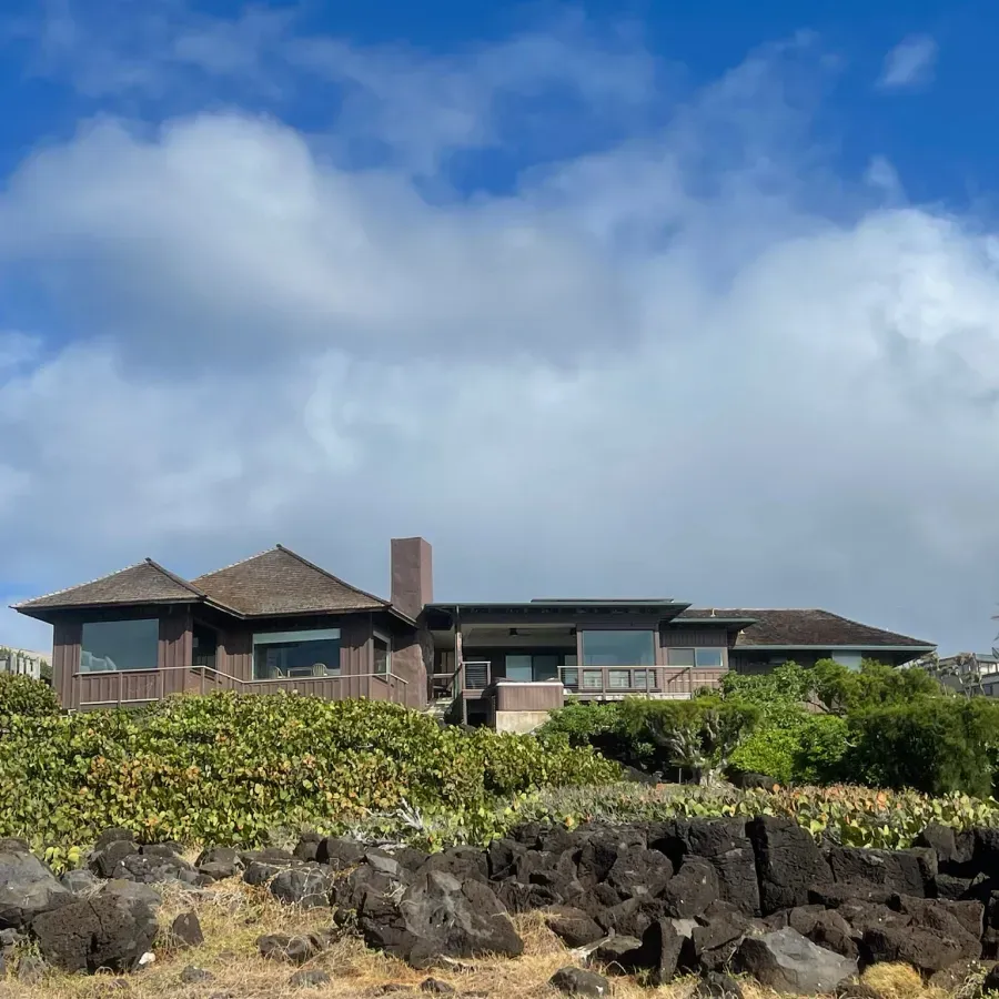 A large house sits on top of a rocky hillside