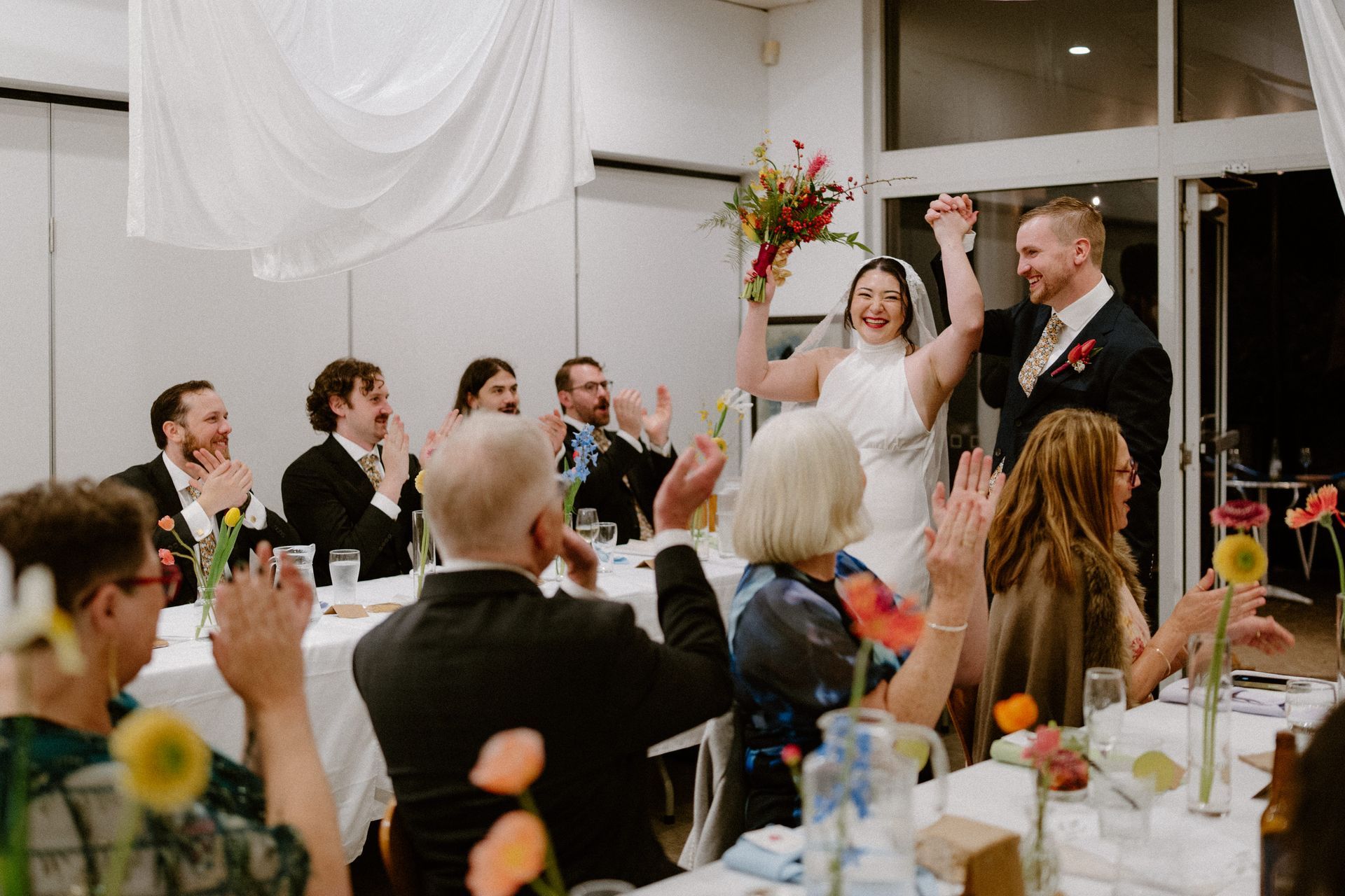 Bride and groom celebrate at a wedding reception as guests applaud and raise glasses — Top Point Café In East Gosford, NSW