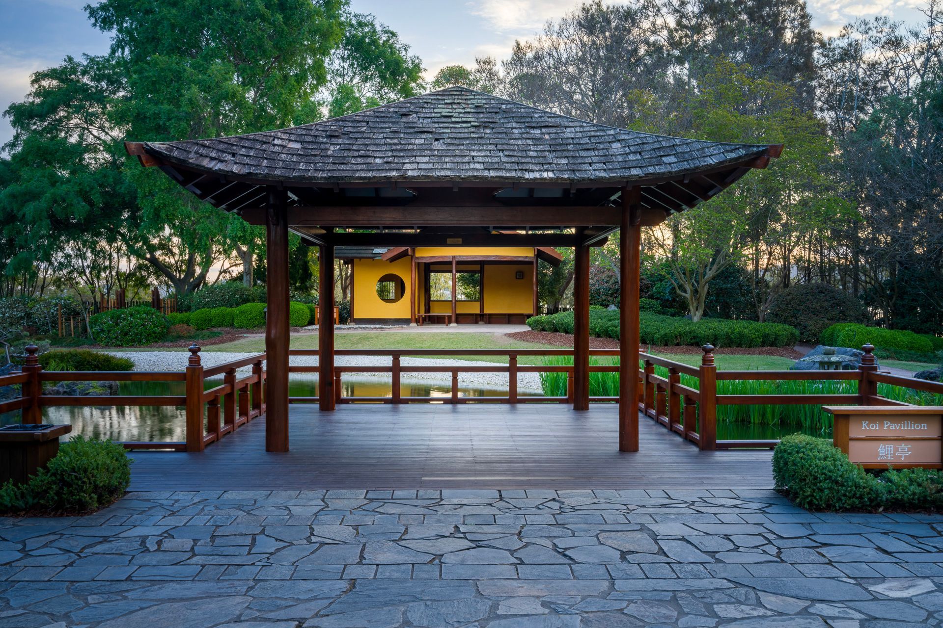 Traditional pavilion entrance in a lush garden at dusk, with wooden railings and stone path — Top Point Café In East Gosford, NSW