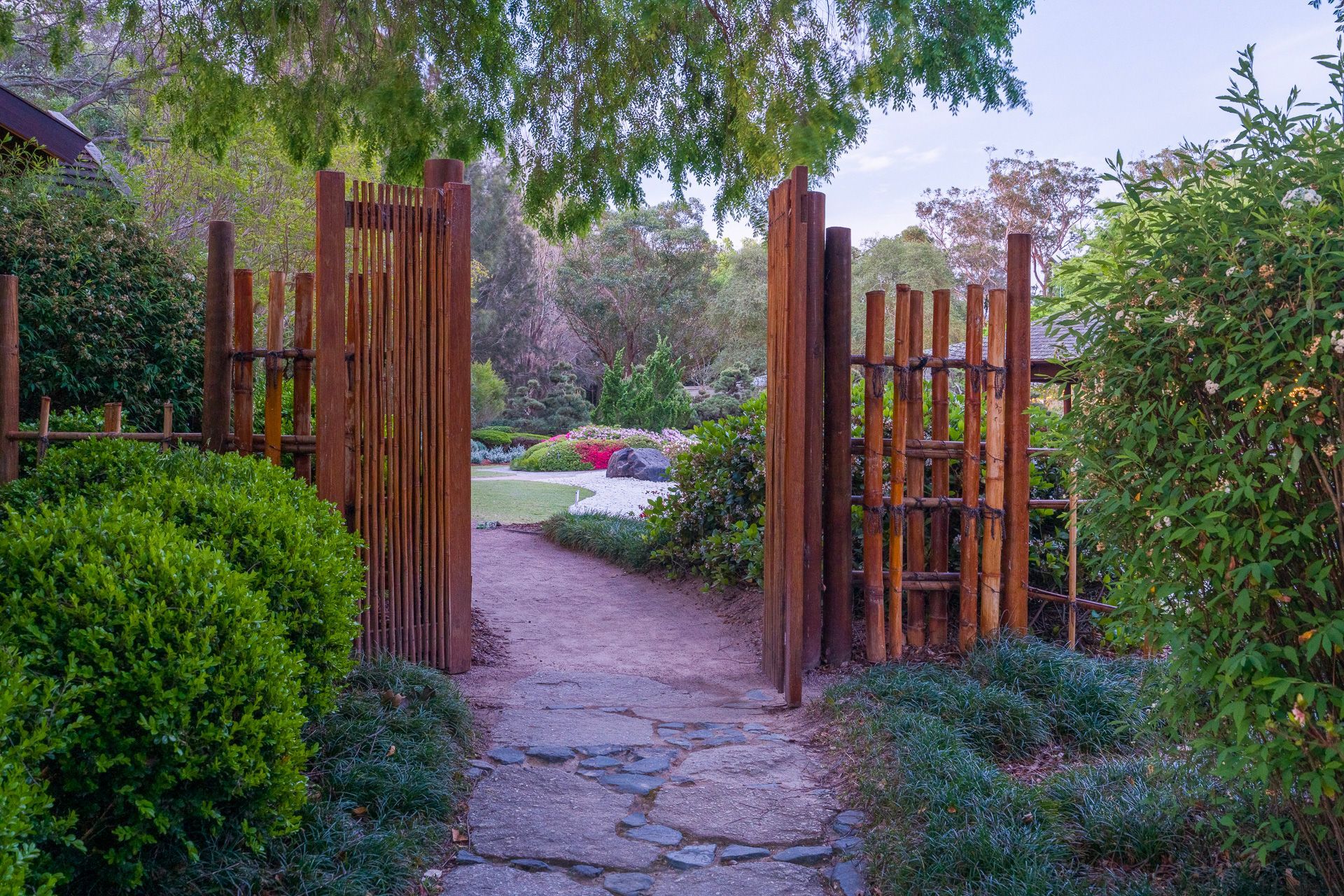 Open wooden garden gate along a stone path leading to colorful flowers and trees — Top Point Café In East Gosford, NSW