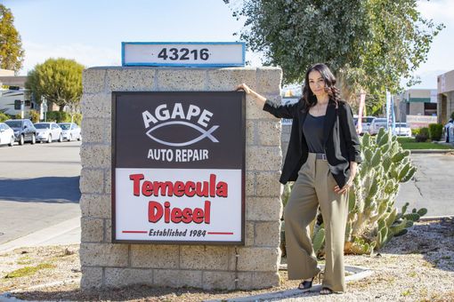 Woman standing beside Agape Auto Repair and Temecula Diesel roadside sign | Agape Auto Repair