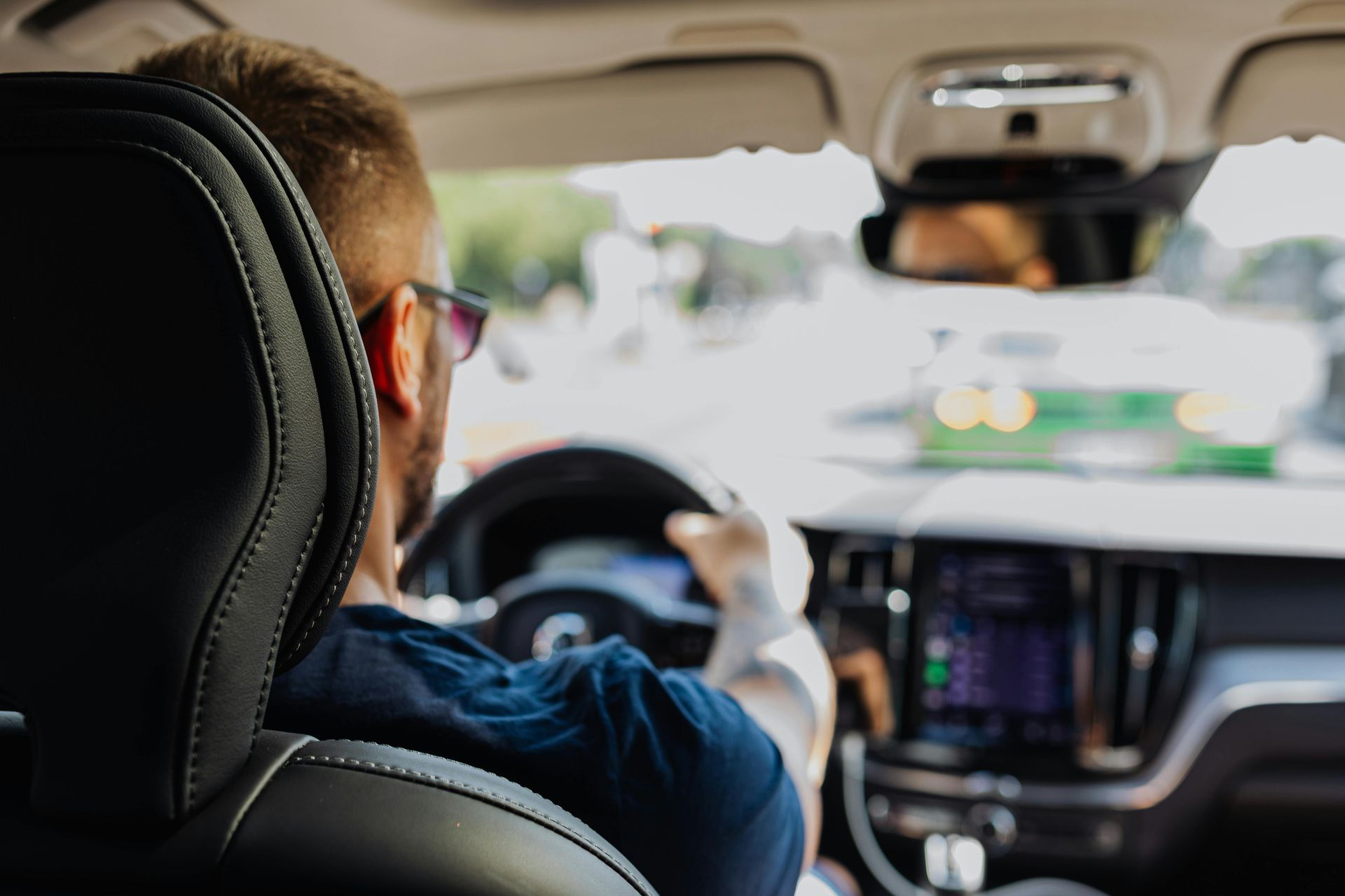 Driver steering a car from the back seat, with a touchscreen dashboard and blurred road ahead | Agape Auto Repair