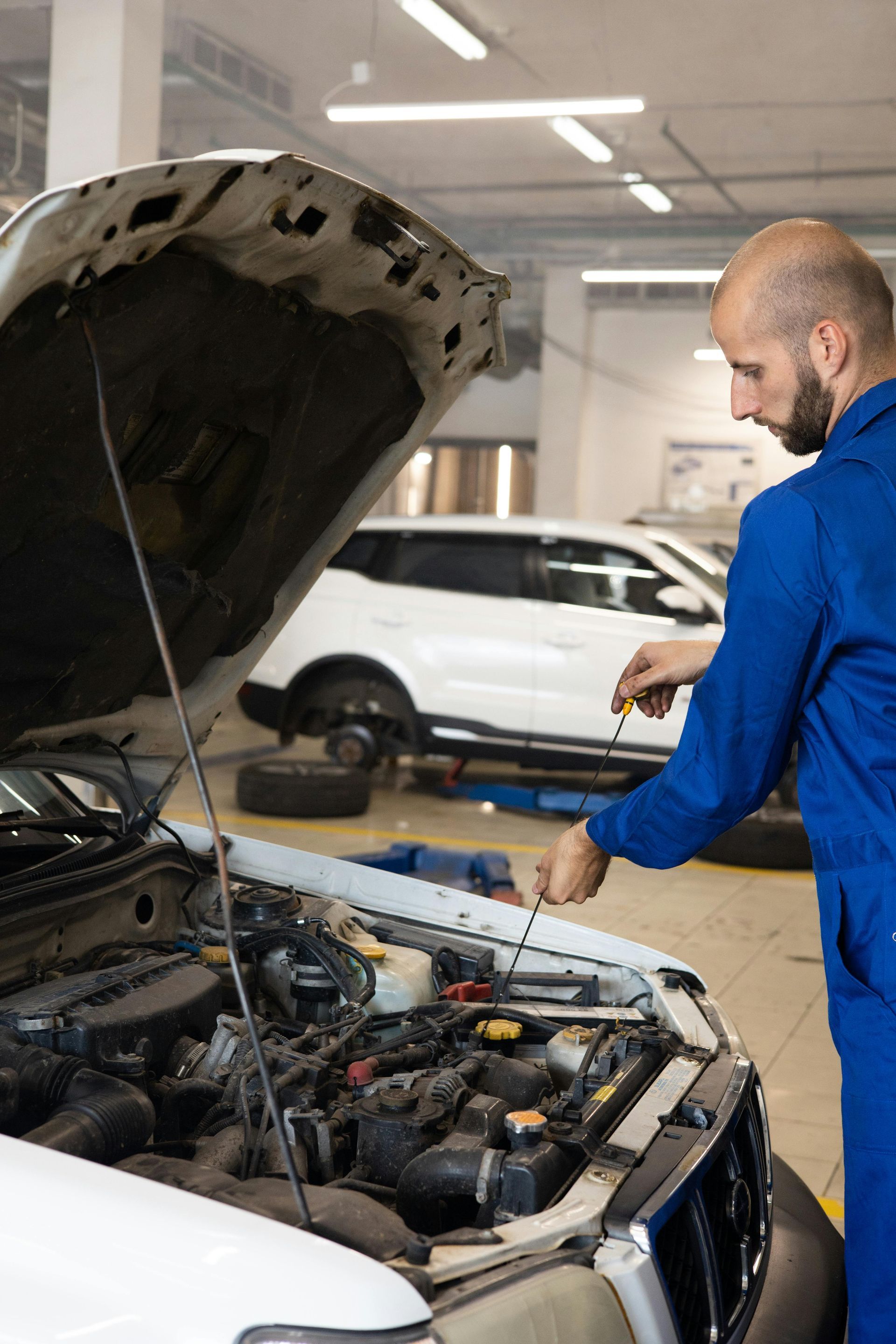 Mechanic inspecting a white car’s open engine bay in a garage | Agape Auto Repair