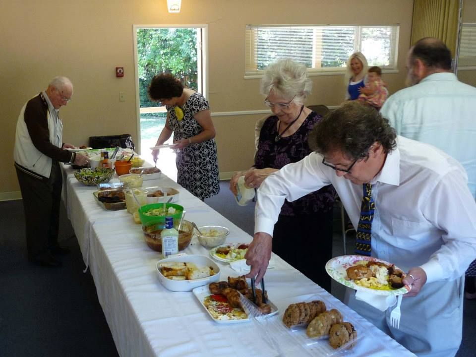 People serving themselves from a buffet table at an indoor event.
