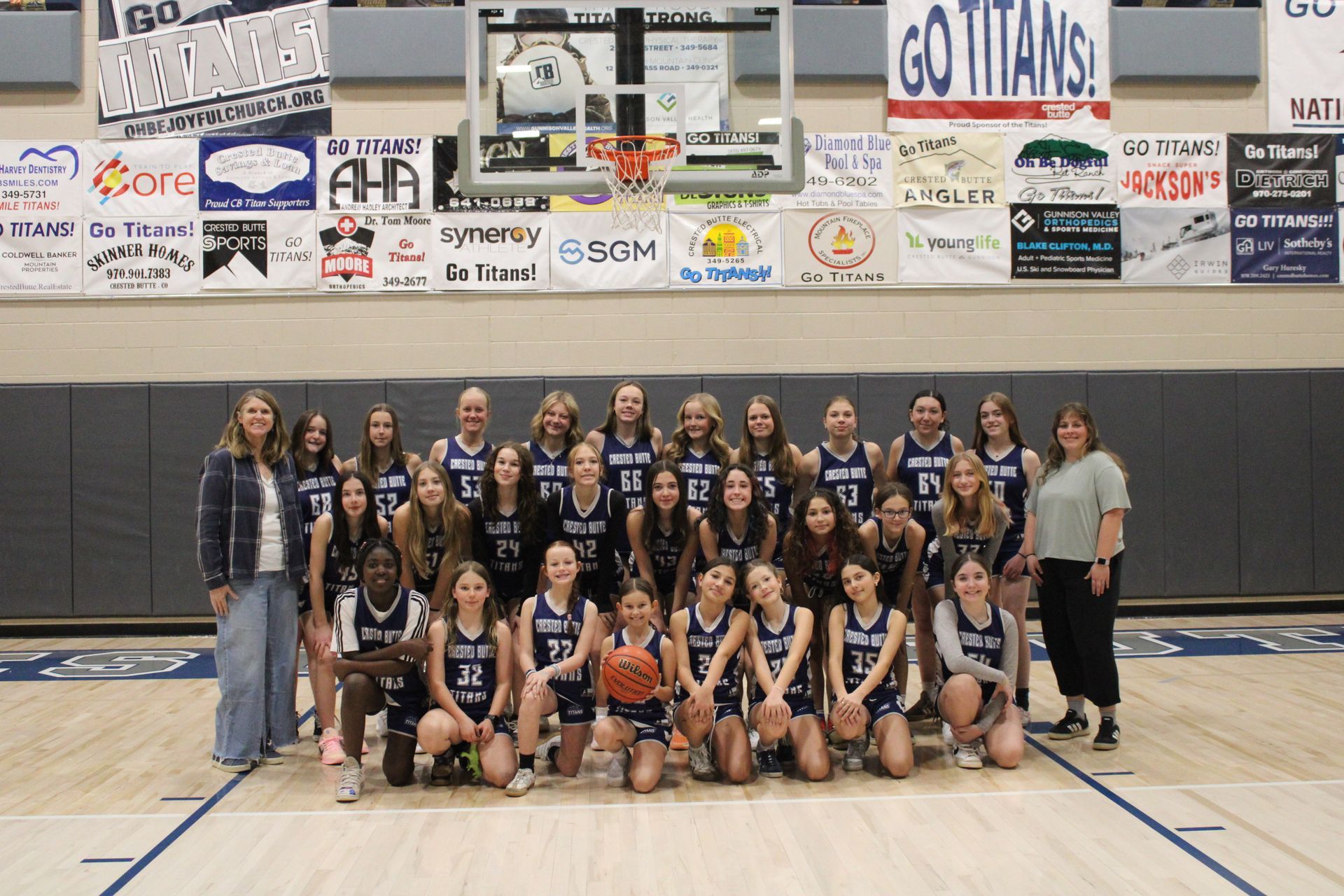 A group of young girls are posing for a picture on a basketball court.