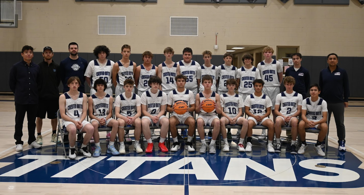A basketball team poses for a team photo in front of a titans logo on the floor.