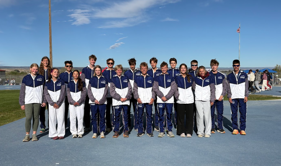 A large group of people are posing for a picture in front of a mountain.