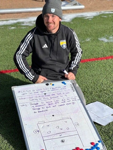 a man is sitting in front of a whiteboard on a field