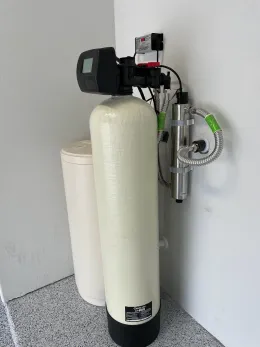 A water softener is sitting on a counter next to a water tank.