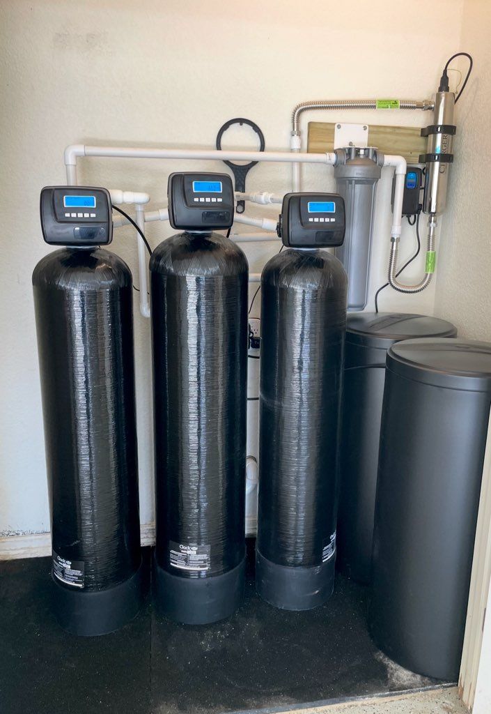 Three black water filters are sitting next to each other in a room.