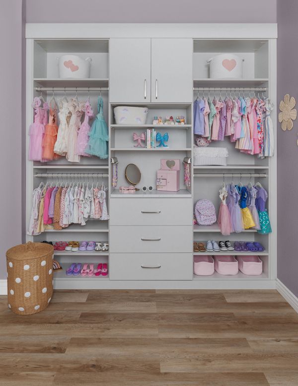 Pink and white kids' closet with hanging clothes, drawers, shelves, and shoes organized neatly