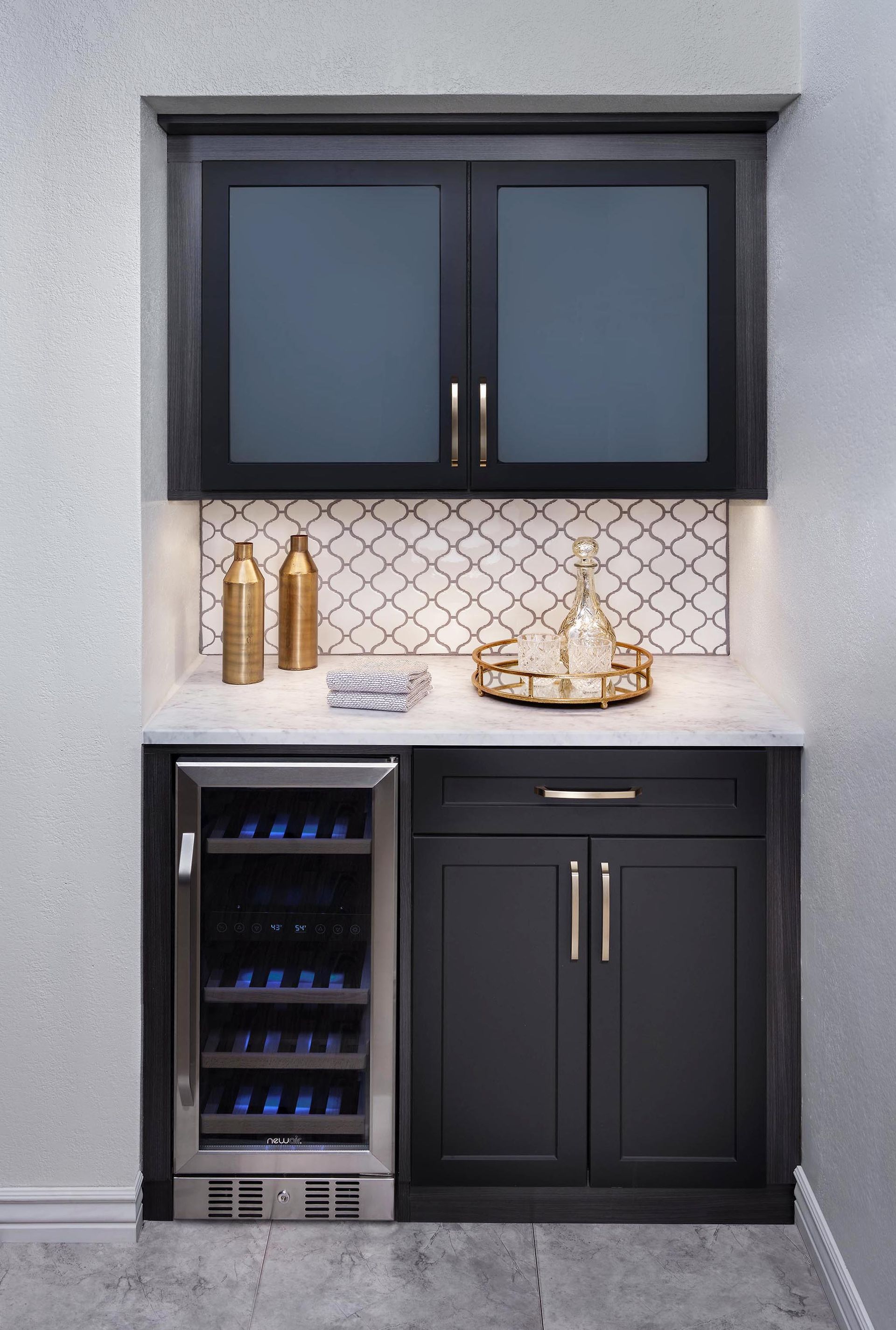 A built-in wet bar with dark wood cabinets, a wine fridge, white stone countertop, and a decorative tile backsplash.