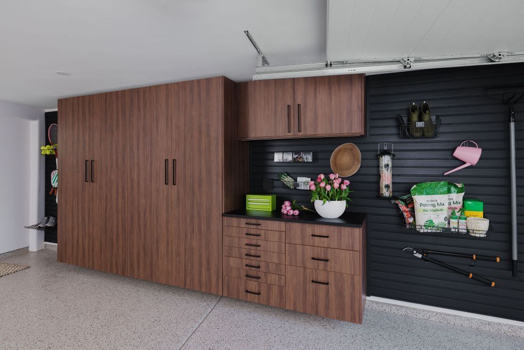a garage with wooden cabinets , a bicycle rack , a ladder , and a workbench .