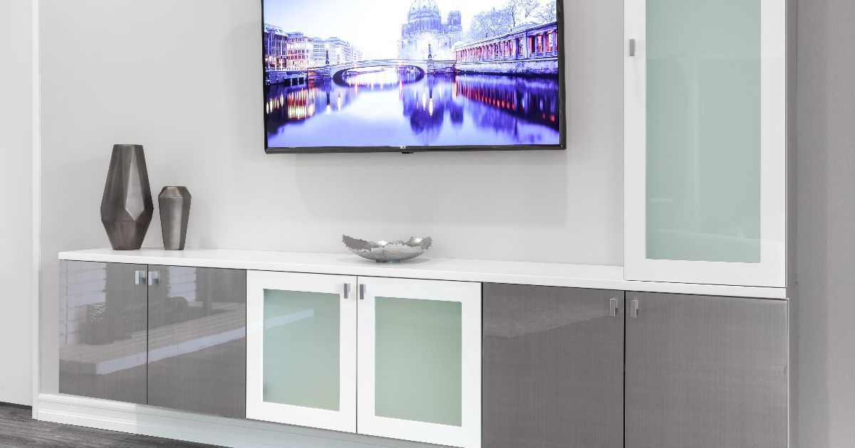 Modern living room with wall-mounted TV, white and gray cabinets, and decorative vases