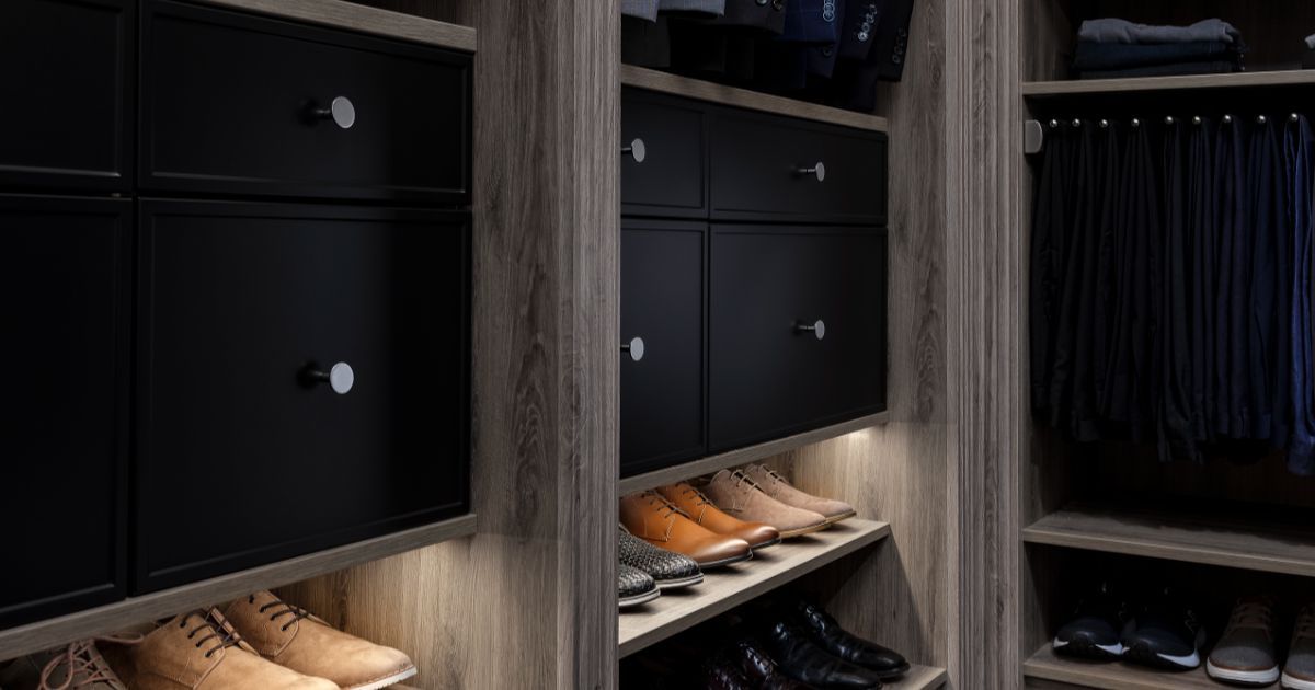 Built-in closet with black drawers, wooden shelves, and neatly arranged shoes and hanging clothes.