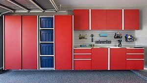 A garage with red cabinets and blue bins.