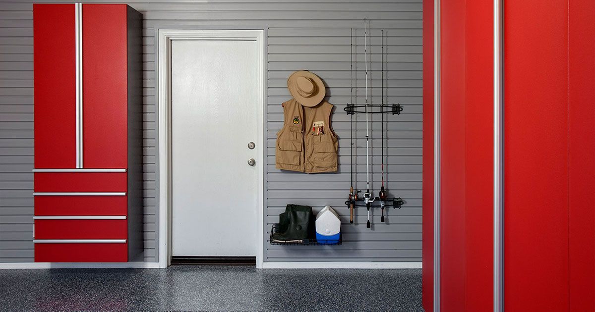 a red motorcycle is parked on a checkered swisstrax floor in a garage .