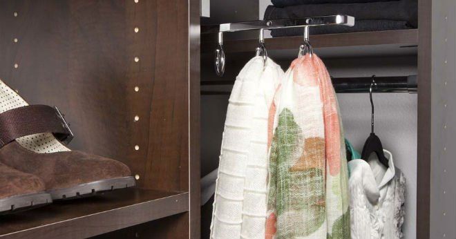 A closet with clothes hanging on hooks and a pair of shoes on a shelf.
