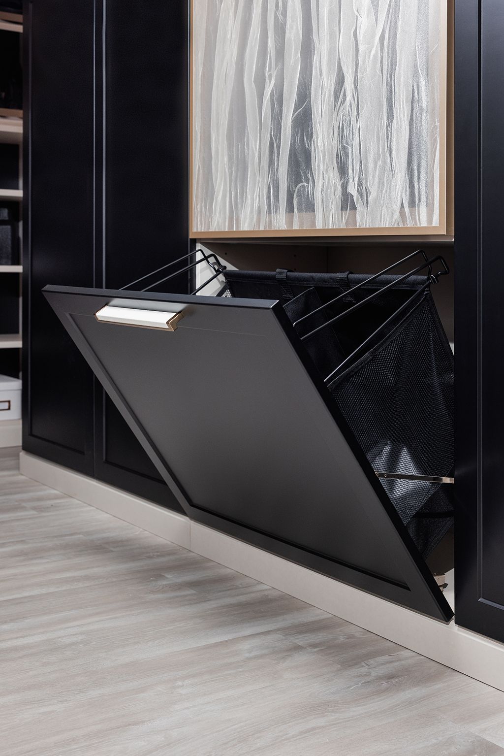 An ironing board in a closet with clothes hanging on it