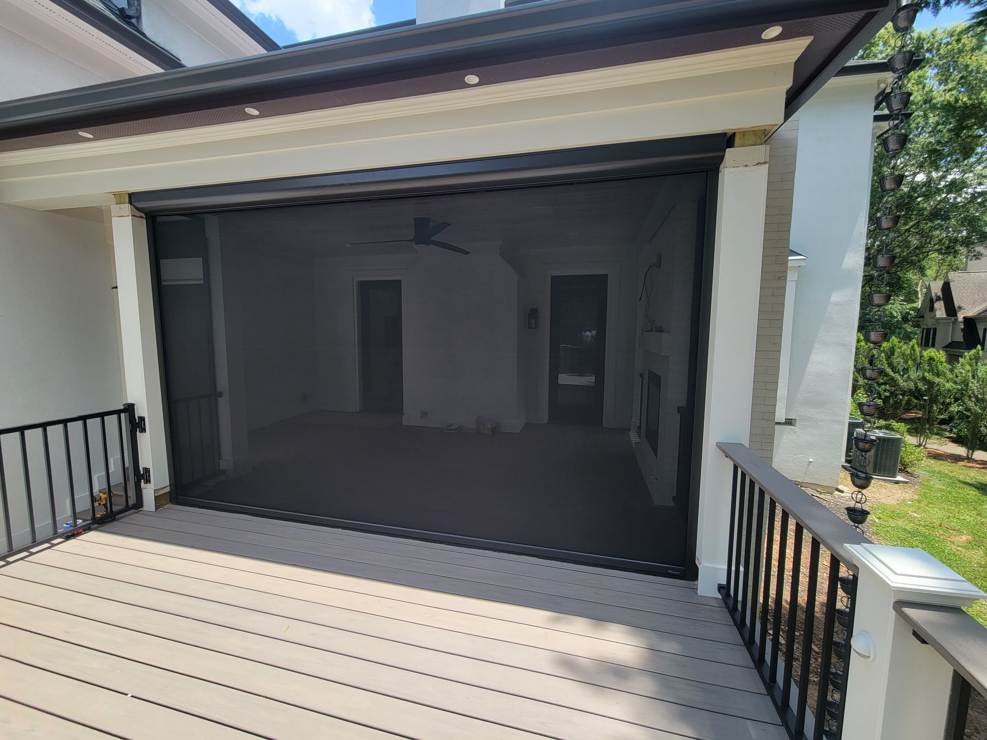 Screened garage opening with concrete floor and front porch railing in daylight