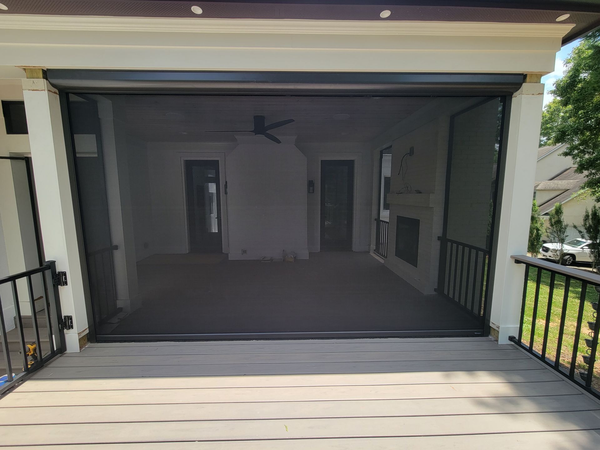 Covered front porch with a dark mesh screen over a doorway and railings on both sides.