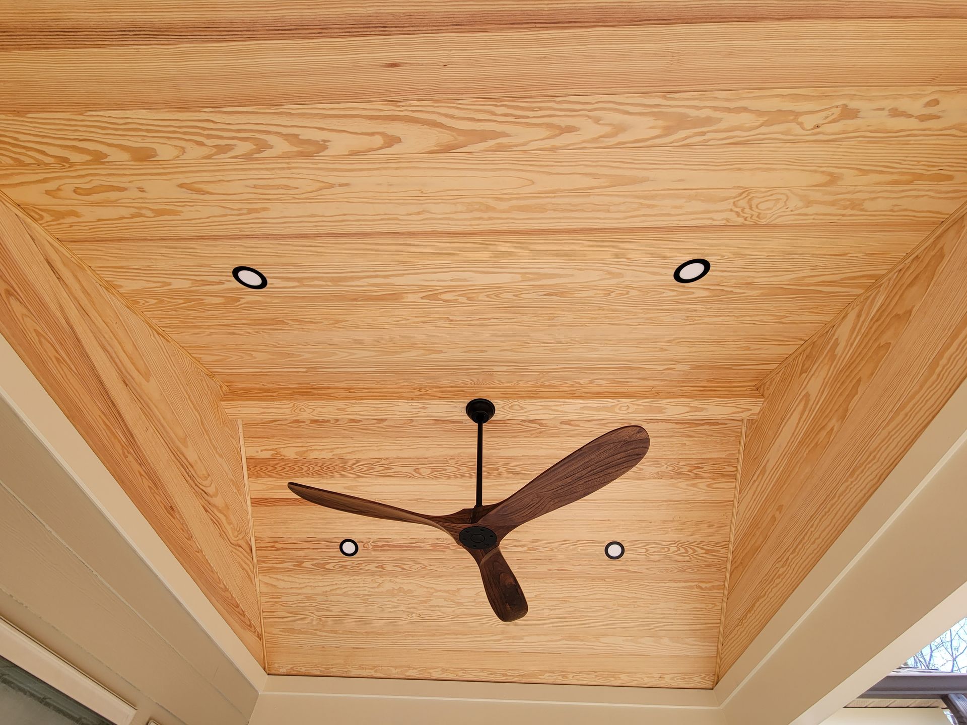 Ceiling with a wooden inlay, recessed lights, and a dark ceiling fan