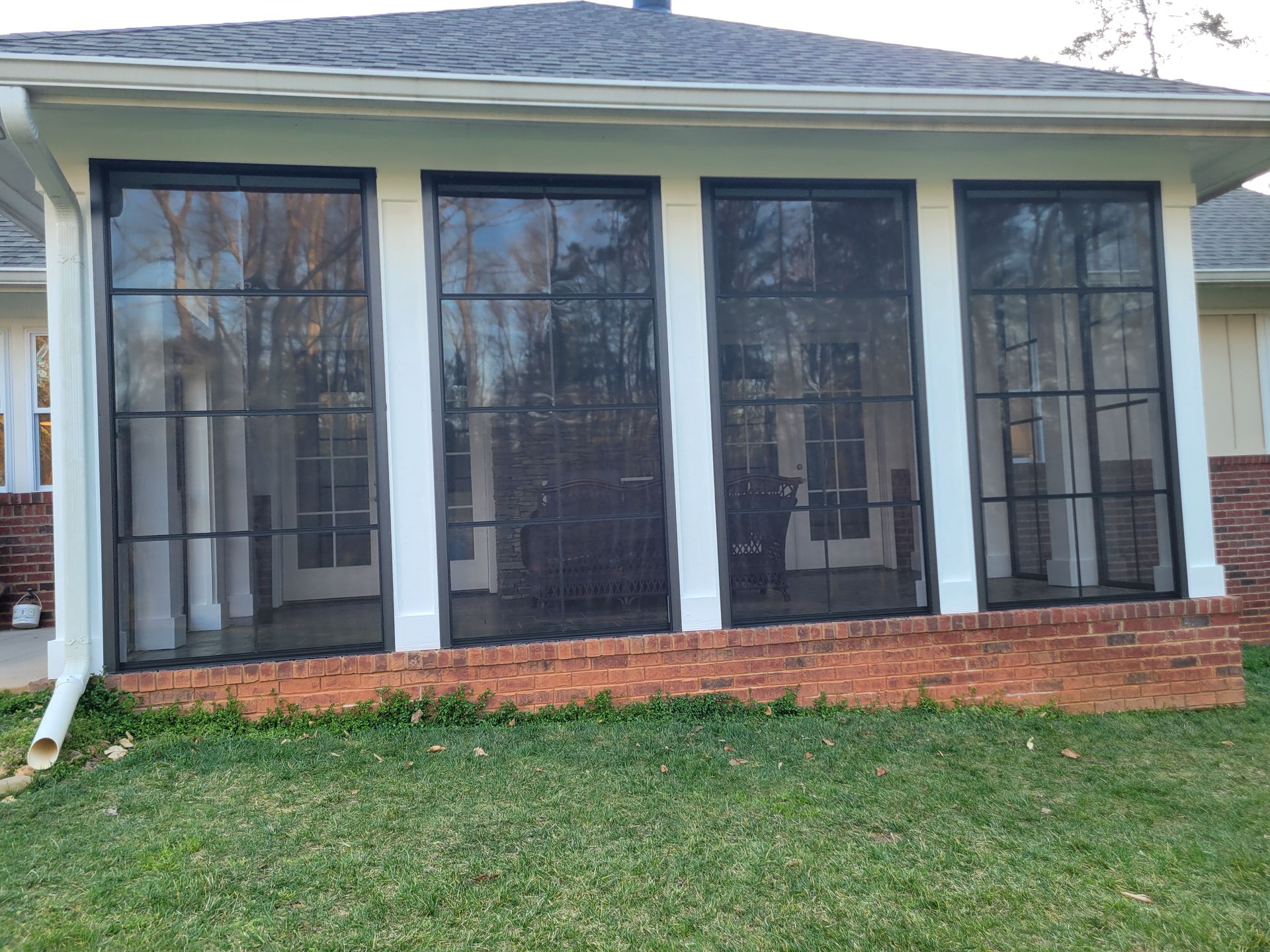 Screened front porch with dark columns and brick base on a small house