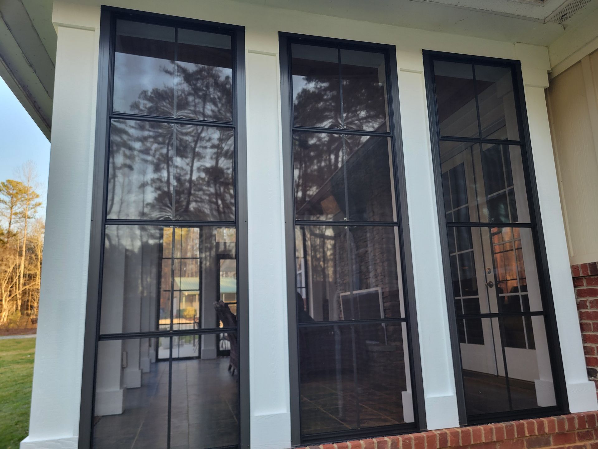 Three tall black-framed glass doors on a white house porch with columns