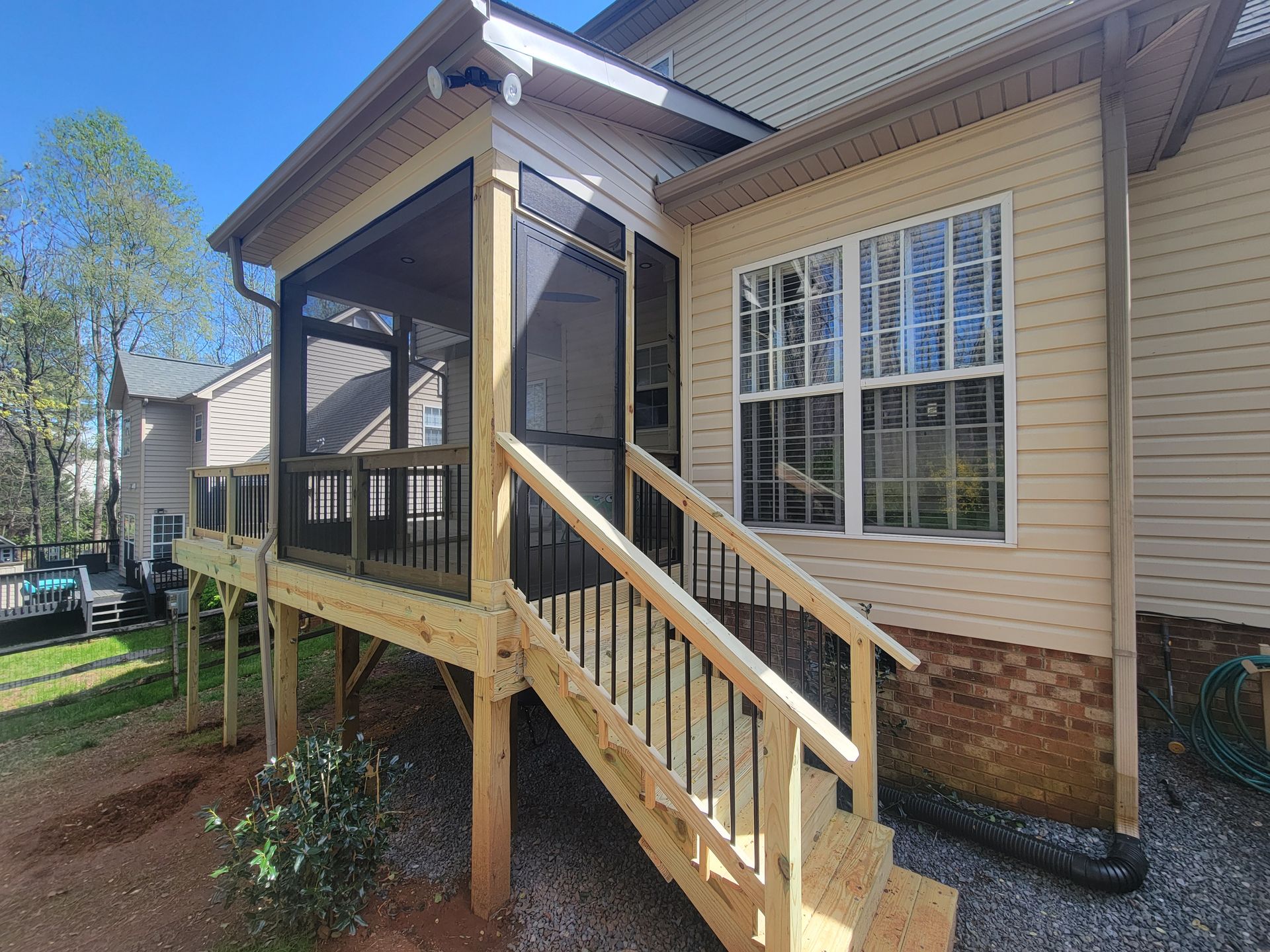 Covered wooden porch with stairs and railing on a beige house exterior