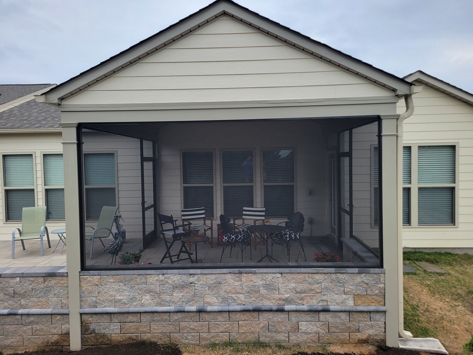 Screened front porch with outdoor table and chairs on a beige house