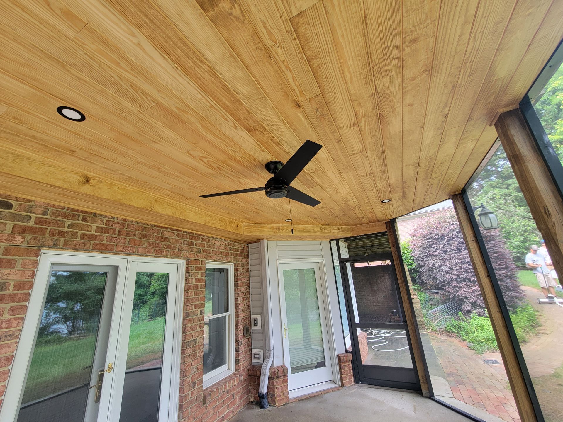 Covered porch with wood ceiling, black ceiling fan, screened windows, and French doors overlooking a yard