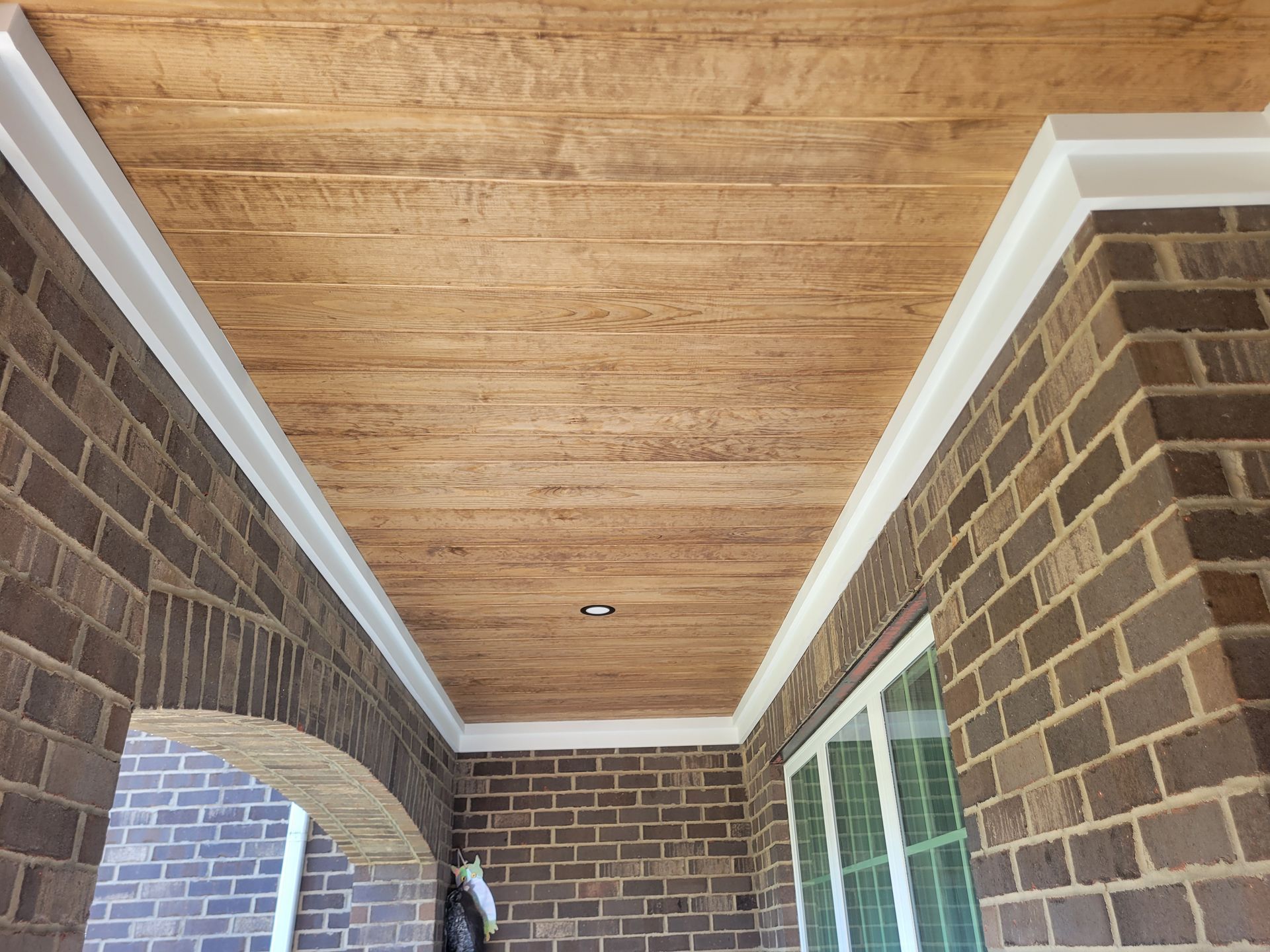 Brick porch ceiling with white trim and a brick wall, viewed from below.