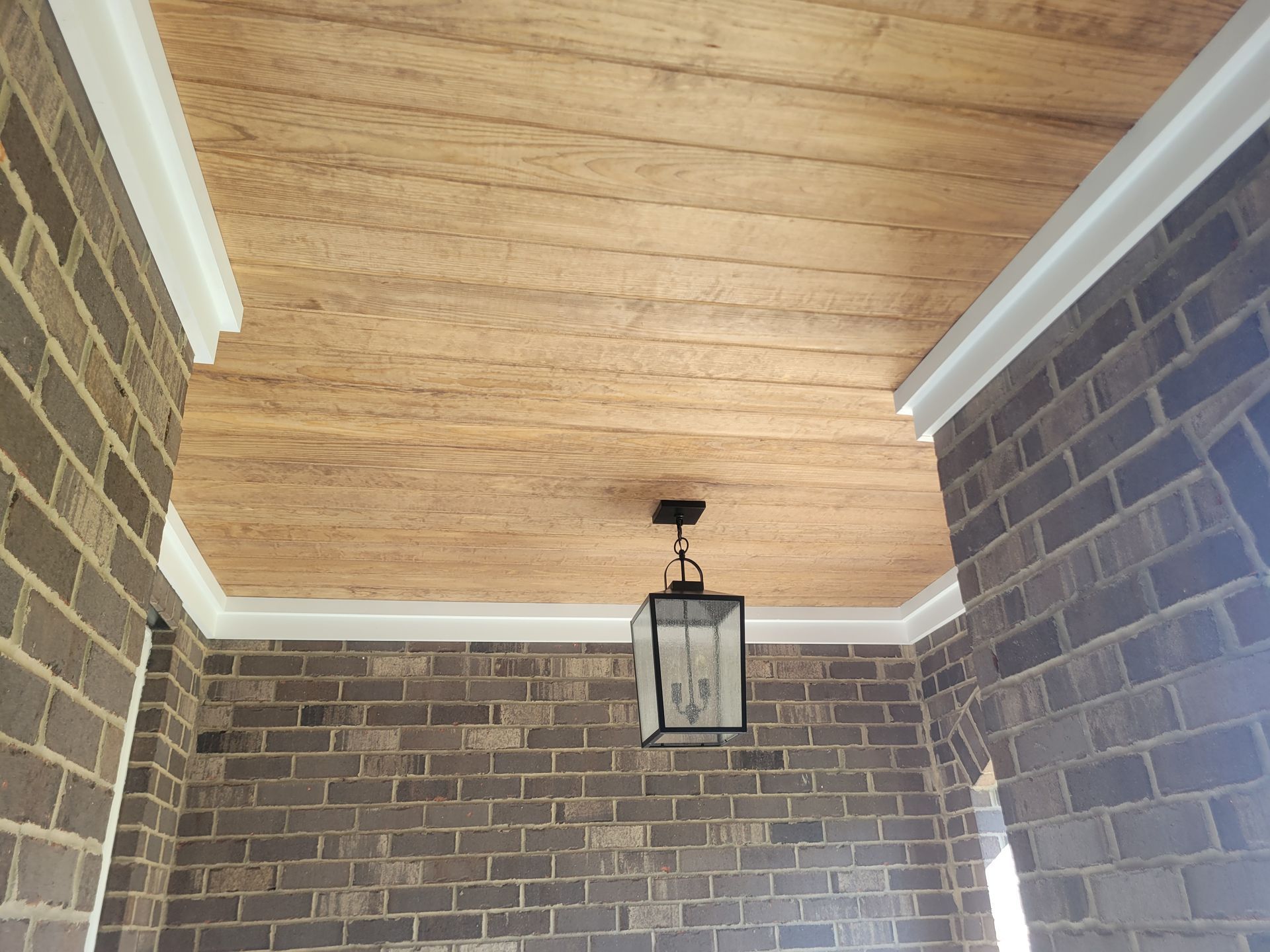 Brick porch ceiling with white trim and a hanging lantern light