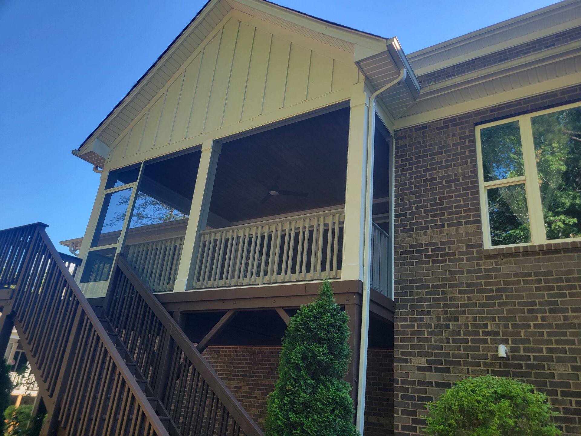 Brick house with a covered porch and stairs under a blue sky