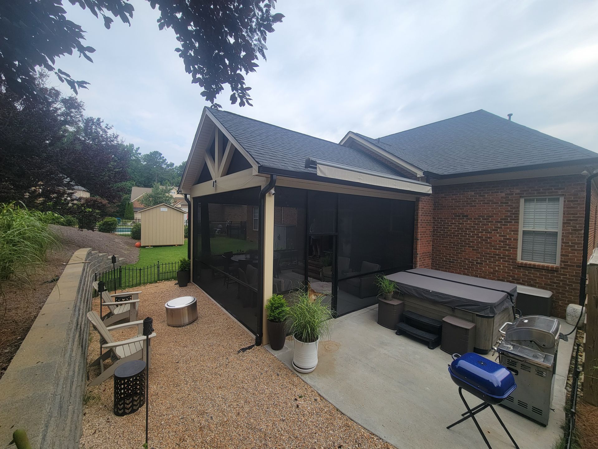 Backyard patio with gravel path, covered seating area, brick house, and potted plants