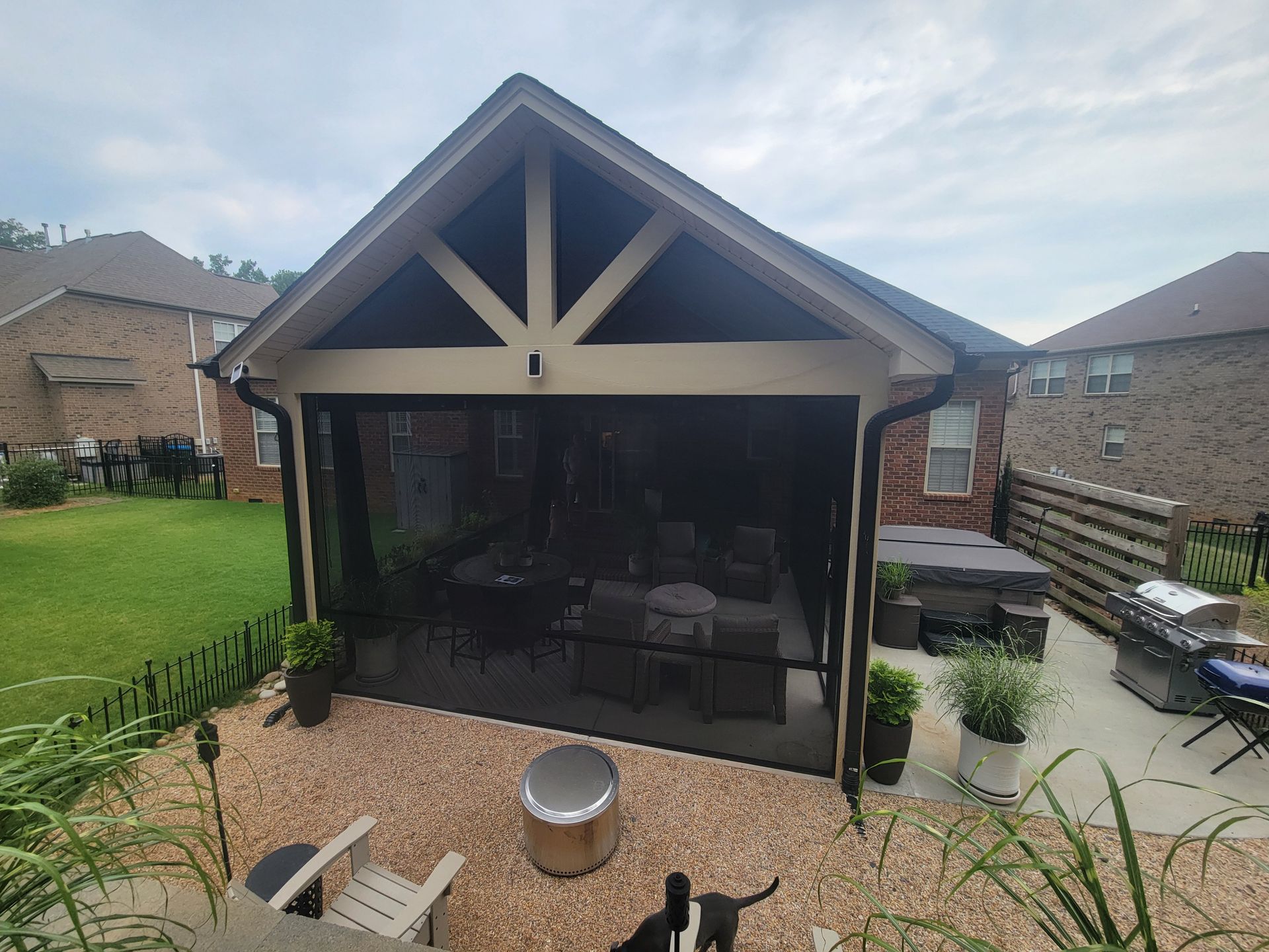Backyard patio with a screened gazebo, seating, fire pit, lawn, and neighboring houses