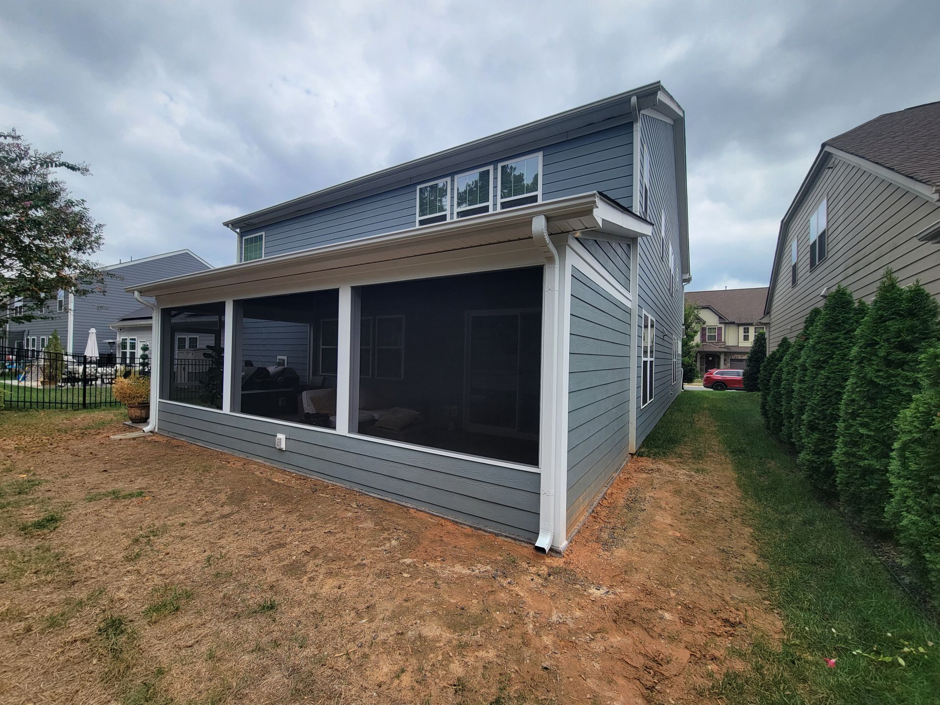 Backyard screened porch addition on a two-story gray house with white trim